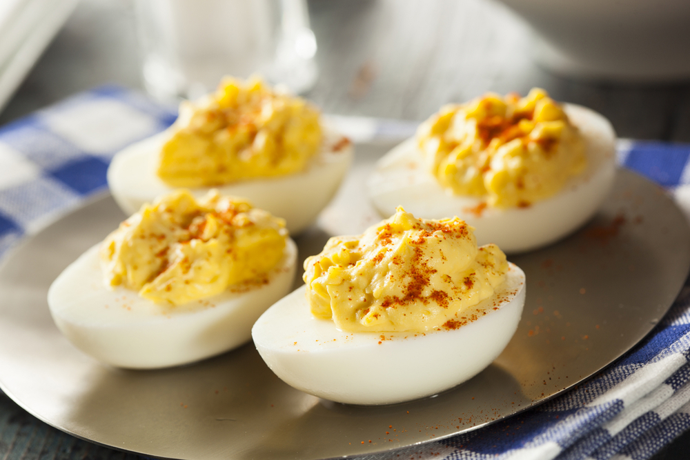 Four deviled eggs on a metal plate.