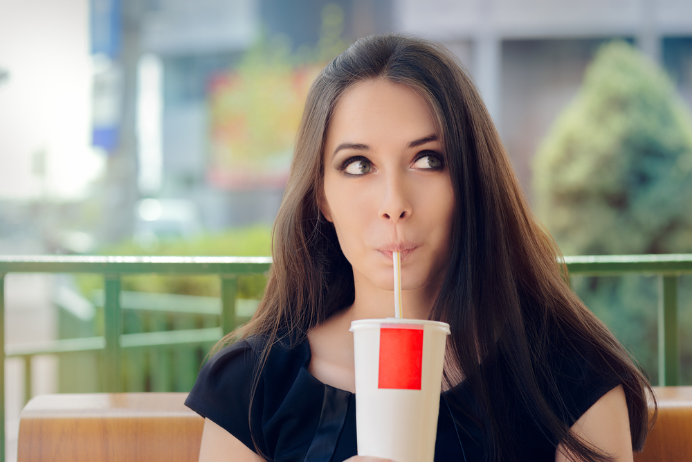 A girl, drinking her large soda while she still can!